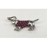 A silver sausage dog brooch with ruby set coat.