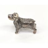 A silver figure of a long haired dog.