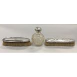 A pair of silver backed brushes together with a solid silver topped scent bottle.