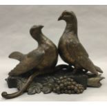A pair of Spelter doves on a plinth with berries, signed L.Carvin