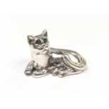 A silver figure of a seated cat with emerald eyes.