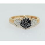 A black/white diamond triple daisy 9ct gold ring. Size L