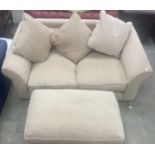 Modern contemporary two seater settee upholstered in beige fabric with matching footstool