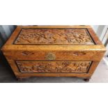 Heavily carved oriental lidded caphor wood chest with depictions of lions on claw feet with brass