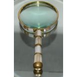 A large magnifying glass with mother of pearl case and brass strapping.