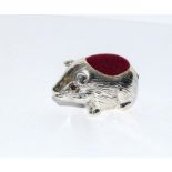 A silver guinea pig shaped pin cushion.