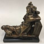 Bronze model of a recumbent clown leaning on some books