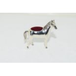 A silver pin cushion in the form of a horse.