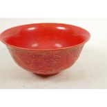 A Chinese porcelain red glazed bowl with embossed decoration of dragons amongst the clouds, six