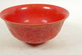 A Chinese porcelain red glazed bowl with embossed decoration of dragons amongst the clouds, six