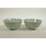 A pair of Chinese celadon glazed porcelain rice bowls with underglaze decoration of carp in a