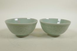 A pair of Chinese celadon glazed porcelain rice bowls with underglaze decoration of carp in a