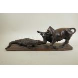 An African carved hardwood figure group decorated with a crocodile attacking a buffalo, 20½" long,