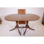 A mahogany twin pedestal dining table, raised on turned columns and splay supports, with extra leaf,