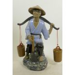 A Chinese, Shiwan style, mud men figure of a workman seated on a rock with his shovel and baskets,