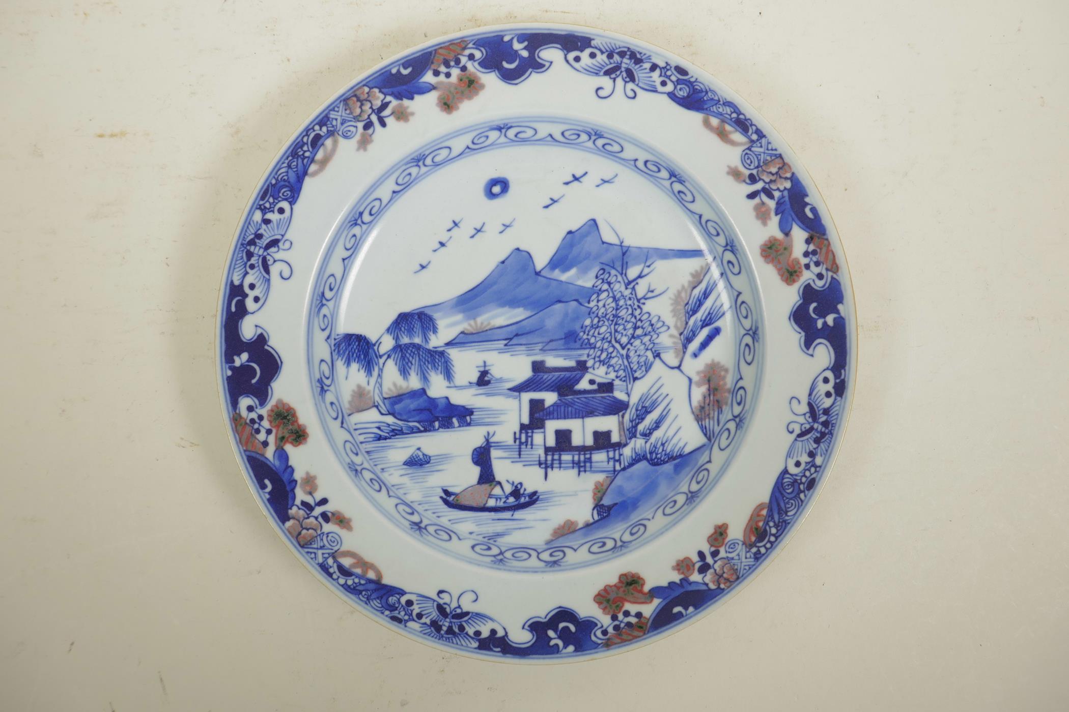 A Chinese blue and white porcelain cabinet plate decorated with a riverside landscape, with red