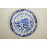 A Chinese blue and white porcelain cabinet plate decorated with a riverside landscape, with red
