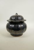A Chinese treacle glazed pottery pot and cover in the form of a gourd, 8" high