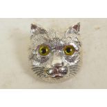 A silver brooch in the form of a cat's head with glass eyes, 1¼" long