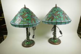 A pair of Tiffany style dragonfly table lamps with bronzed and jewelled decoration on a green