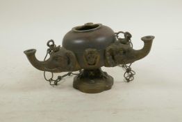 A bronze and copper hanging oil lamp with three elephant head fonts, 6½" wide