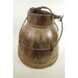 An Oriental wooden water jar of bound stave construction, with rope carry handle, 14½" high, 16"