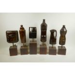 A collection of six carved and lacquered wood storage bottle maquettes, mounted on display