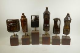 A collection of six carved and lacquered wood storage bottle maquettes, mounted on display