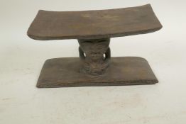 An African carved wood headrest with figural decoration, 5" high, 9" wide