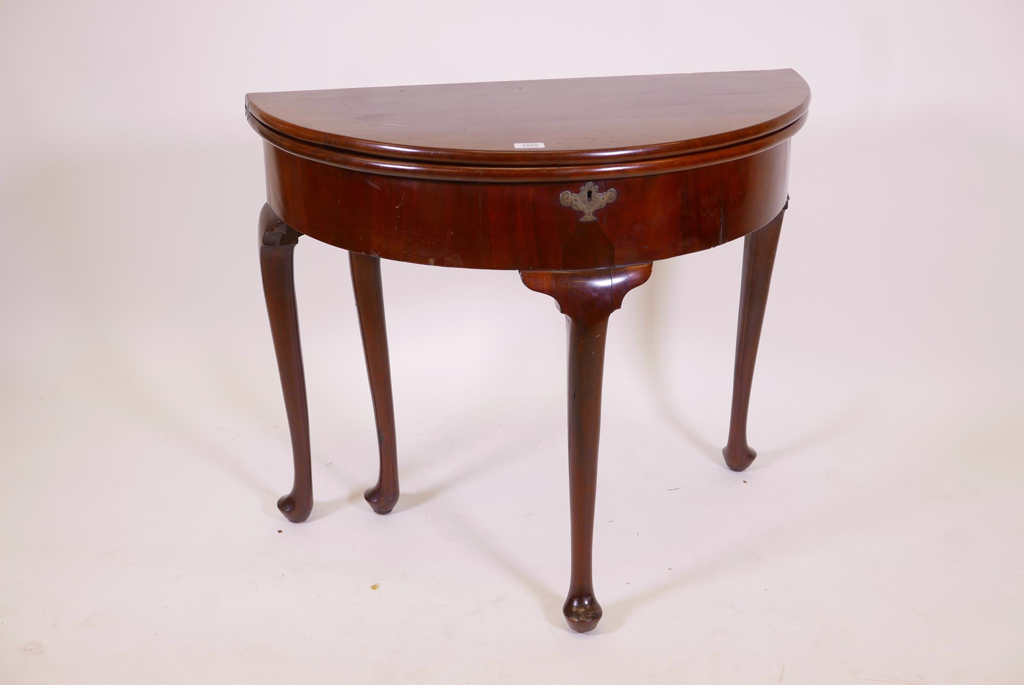 A Georgian mahogany demi lune card table, with two folding leaves opening to reveal a well, raised