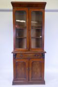 A Victorian inlaid figured mahogany bookcase, the upper section with two glazed arched doors, the