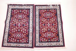 A pair of small Turkish rugs with stylised floral pattern on a red ground, 38" x 24"