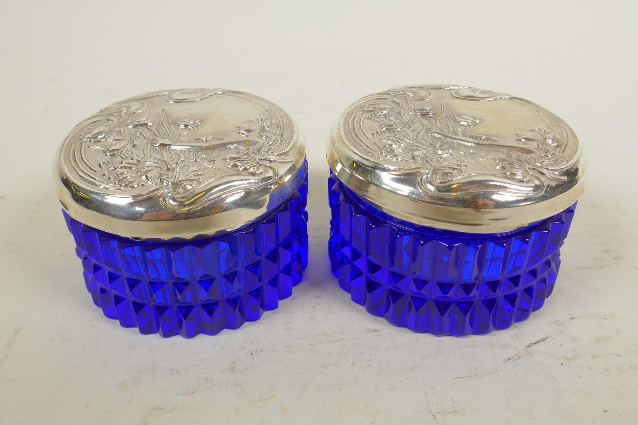 Two blue glass dressing table jars with sterling silver lids embossed with Art Nouveau designs,