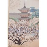 A Japanese woodblock print of a temple in a landscape of blossom filled trees, labelled verso, The