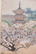 A Japanese woodblock print of a temple in a landscape of blossom filled trees, labelled verso, The