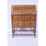 A 1930s Jacobean style oak bureau, with panelled fall front over two drawrers, raised on bulbous