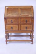 A 1930s Jacobean style oak bureau, with panelled fall front over two drawrers, raised on bulbous