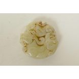 A Chinese mottled white jade pendant with carved dragon and kylin decoration, 2" diameter