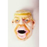 A wall mounted iron bottle opener cast as a caricature of Donald Trump, 4" long