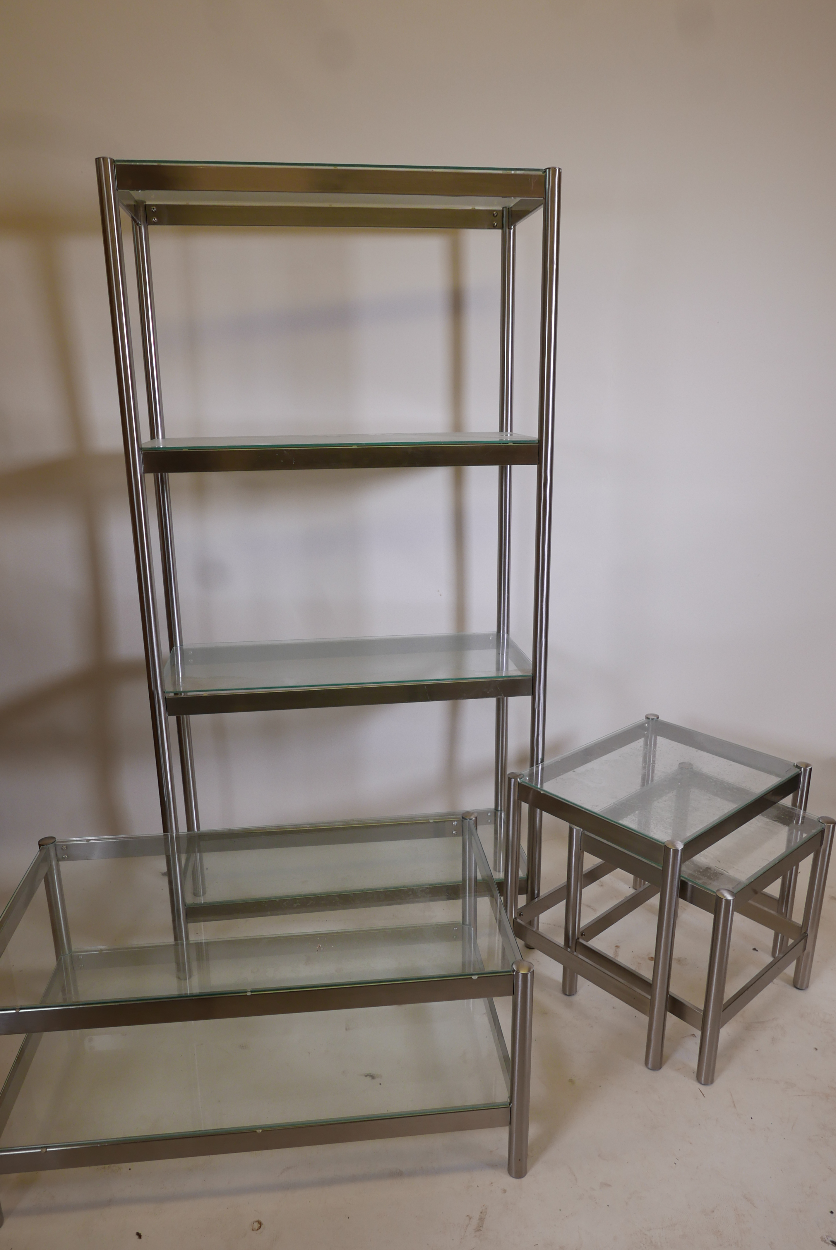 A contemporary brushed steel open display unit with glass shelves and matching occasional table, 31"