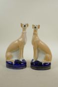 A pair of cast pottery Staffordshire style greyhounds, 8½" high, A/F, chip to ear