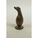 An Oriental bronzed metal ornament in the form of a crocodile hatching from an egg, indistinct marks