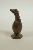 An Oriental bronzed metal ornament in the form of a crocodile hatching from an egg, indistinct marks