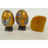 A pair of Chinese decorative cloisonne eggs on wooden stands, together with a carved soapstone