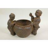 A Chinese cast iron pot, 5" diameter, with figures of children to either side, 4 character mark to