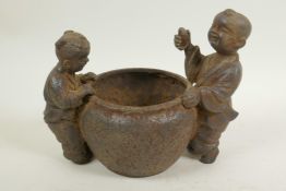 A Chinese cast iron pot, 5" diameter, with figures of children to either side, 4 character mark to