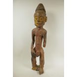 An African carved hardwood figure of a male nude, with traces of red and yellow paint, 24½" high,