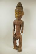 An African carved hardwood figure of a male nude, with traces of red and yellow paint, 24½" high,