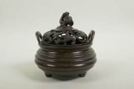 A Chinese bronze censer of ribbed form with two phoenix eye handles, a pierced cover decorated