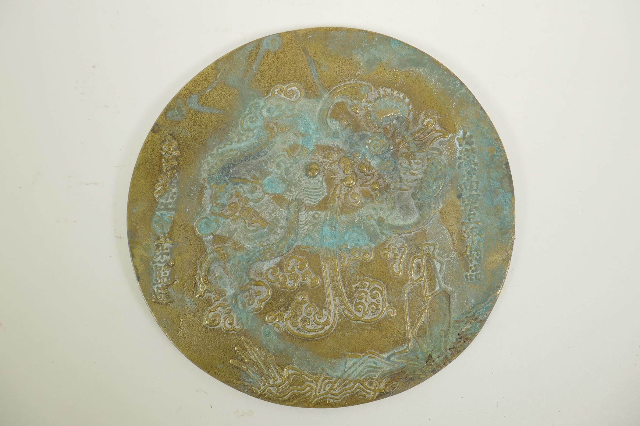 A Chinese bronze circular plaque with raised dragon and character decoration, 9½" diameter